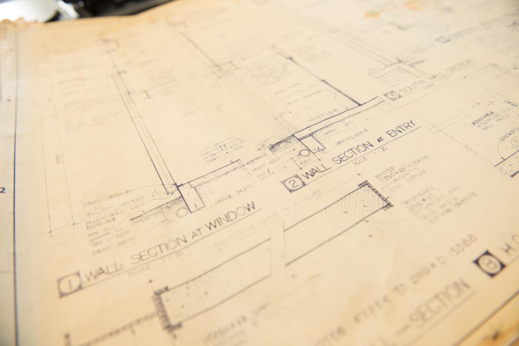 A close-up viewpoint on a yellowed manila surface, etched with architectural drawings